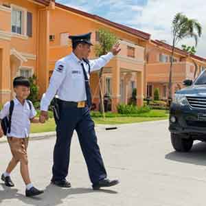 A security guard of Camella Homes Cavite, helping a kid cross the street.